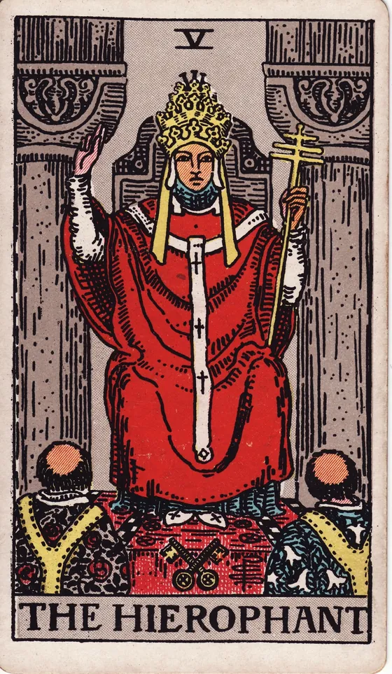 Tarotkarte Der Hierophant: Ein Lehrer sitzt zwischen zwei Säulen und hebt die Hand zum Segen. Vor ihm knien zwei Menschen, zu seinen Füßen liegen zwei gekreuzte Schlüssel.