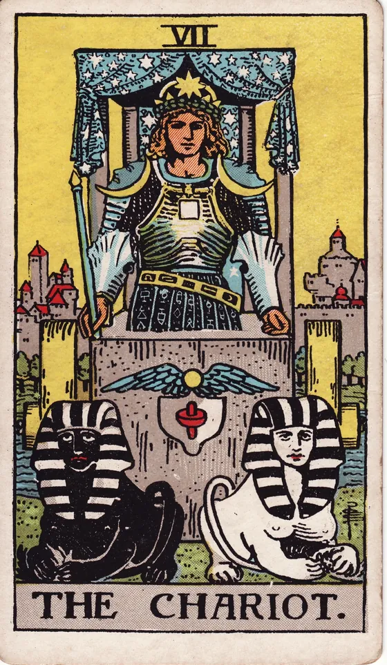 Tarotkarte Der Wagen: Ein junger Mann steht in einem Wagen unter einem Himmel aus Sternen. Vor ihm liegen zwei Sphingen, eine helle und eine dunkle. Zügel hält er keine.