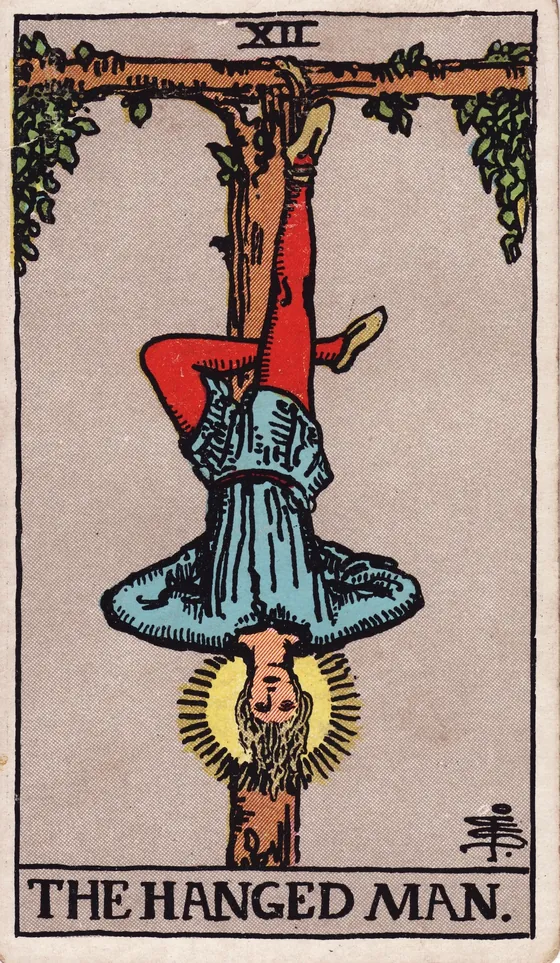 Tarotkarte Der Gehängte: Ein junger Mann hängt kopfüber an einem Baum, ein Bein angewinkelt. Sein Gesicht ist ruhig, um seinen Kopf leuchtet ein Schein.